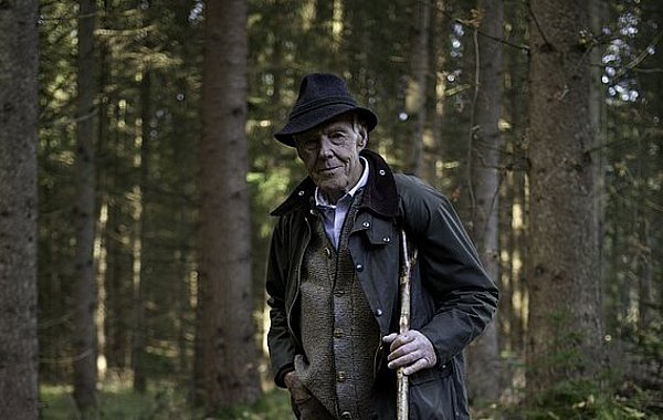 Josef Göppel - Förster und Bundestagsabgeordneter ©Lennart Laberenz Josef Göppel steht im Wald, nehmen ihm sitzt sein Jagdhund Akso.
